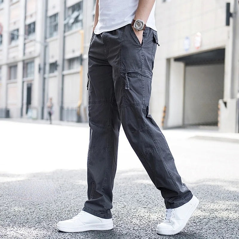 Mann in grauer Cargohose und weißen Sneakers auf städtischer Straße. Modetrend, lässiger Stil, Herrenbekleidung, urbane Mode.