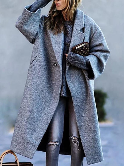 Frau in grauem Oversize-Mantel, kombiniert mit zerrissenen Jeans und einem Buch in der Hand. Modetrend, Herbstmode, lässiger Stil.