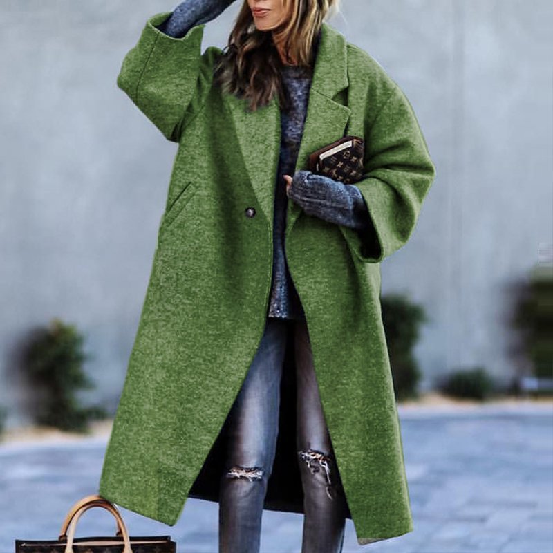 Frau in grünem Oversize-Mantel, zerrissene Jeans, grauer Pullover, hält eine Tasche. Modetrend Herbst/Winter, stilvolle Damenbekleidung.