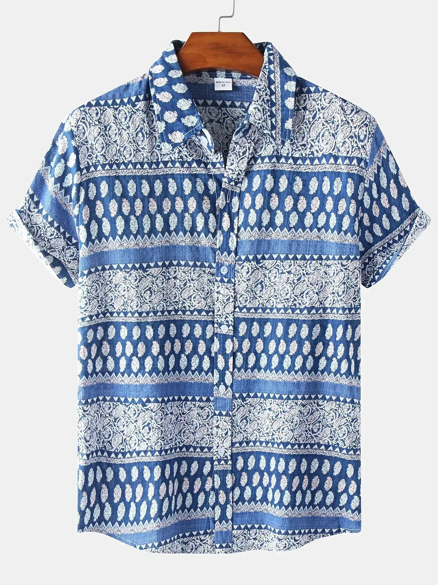 Blau-weißes Herrenhemd mit Paisley-Muster, kurzärmelig, aus Baumwolle, auf Holzkleiderbügel. Ideal für Sommermode und Freizeitkleidung.
