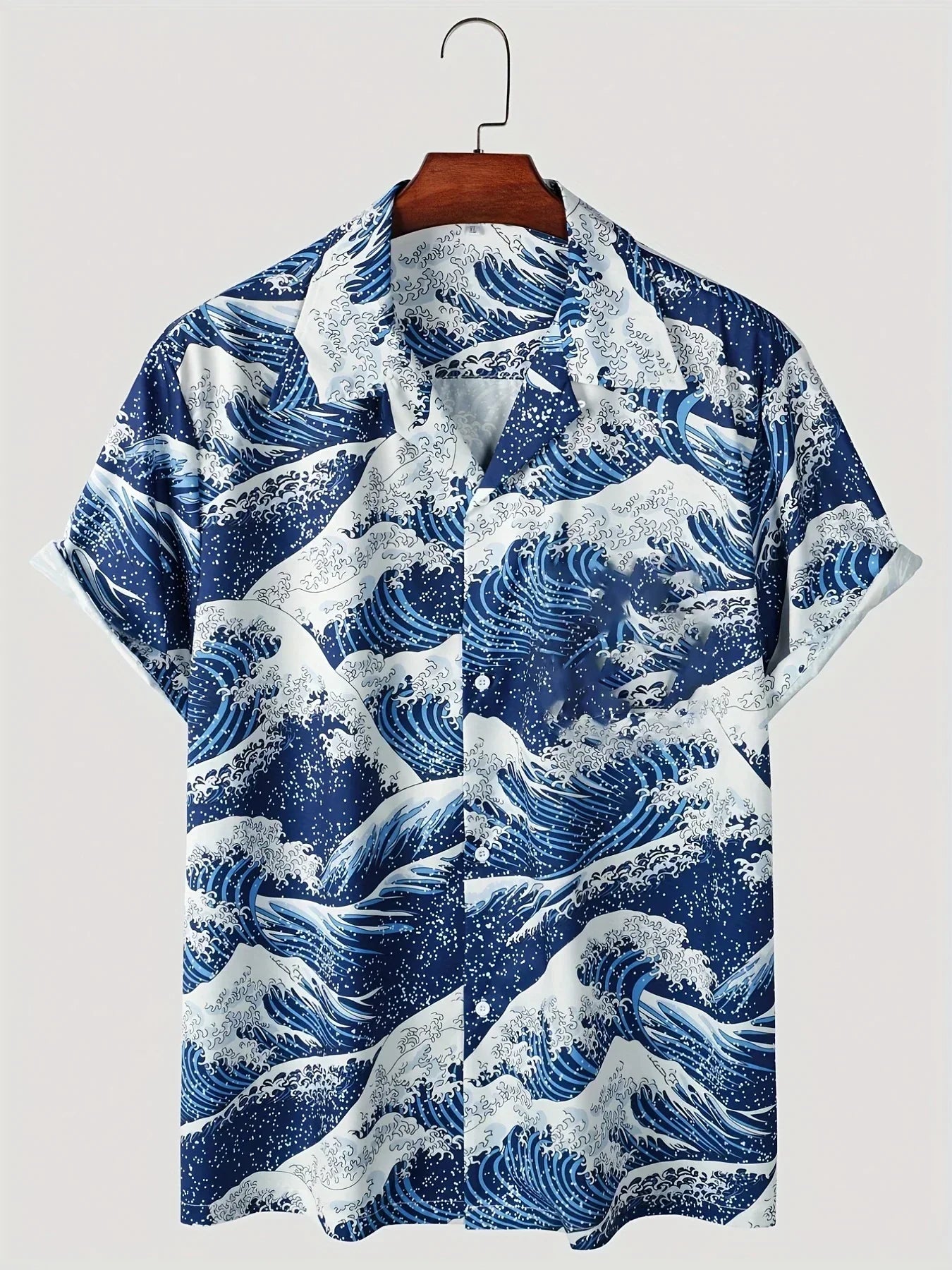 Kurzarmhemd mit blau-weißem Wellenmuster, inspiriert von japanischer Kunst, auf Holzkleiderbügel. Sommermode, Herrenhemd, maritimes Design.